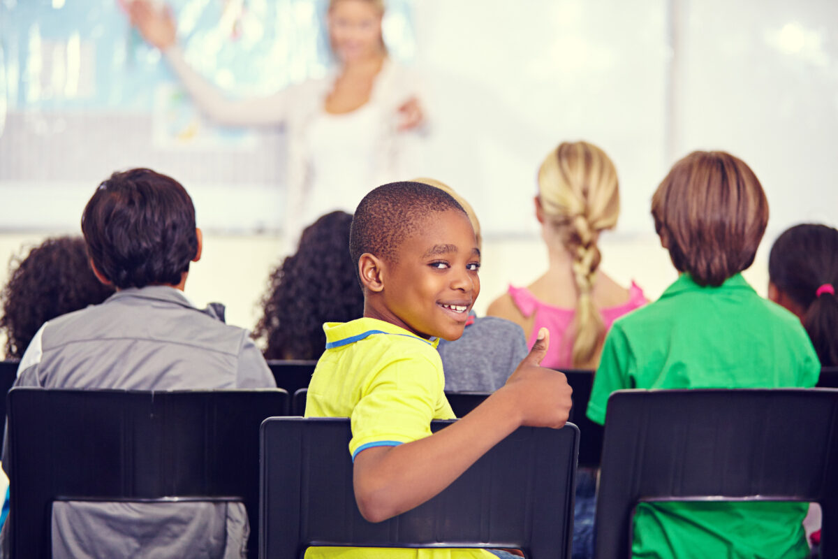 Un garçon fait un pouce en l'air dans une classe